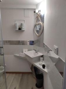 Un baño blanco con lavabo y espejo. en Residenza le Torri, en Bolonia