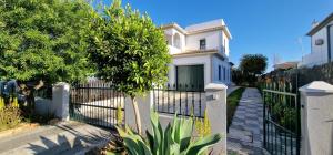 uma casa branca com uma cerca e uma árvore em Villa Pretty em Almancil