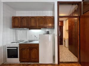 a kitchen with a white refrigerator and wooden cabinets at Boka Place - Sutomore in Sutomore