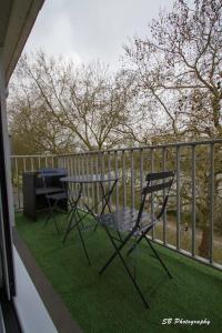 2 Stühle und ein Tisch auf einer Veranda mit einem Zaun in der Unterkunft L'Inattendu - Les Maisons de Madeleine in Nantes