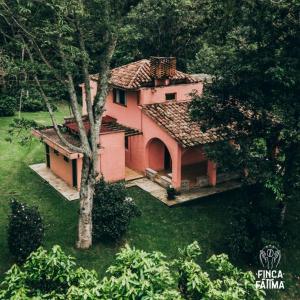 a small pink house in the middle of a yard at Cabaña en cafetal de Coatepec in Coatepec