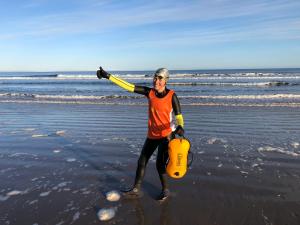 a man walking on the beach with a life vest and aqual at Driftwood Cottage, Findhorn Village in Forres