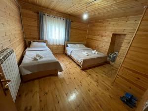 a bedroom with two beds in a wooden cabin at Bujtina ZEMRA TRADITES in Theth