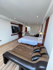 Hotel SOGU TOWER في اياكوتشو: غرفة نوم مع أريكة أمام سرير