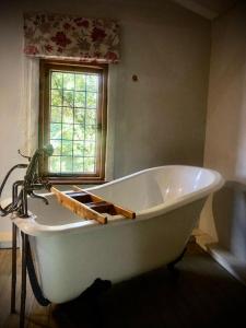 baño con bañera blanca y ventana en Mill Lane Farmhouse, en Hartbeespoort