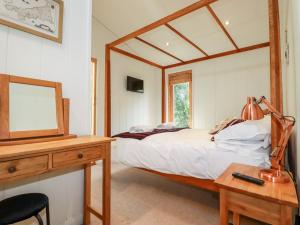 a bedroom with a bed and a desk with a mirror at 7 Stonerush Valley in Looe