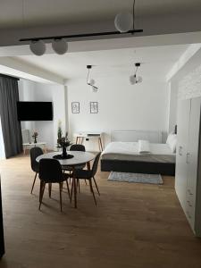 ein Wohnzimmer mit einem Tisch, Stühlen und einem Bett in der Unterkunft Forest Boutique in Piteşti