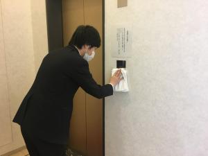 a man wearing a mask putting a napkin on a door at Swanky Hotel Otomo - Vacation STAY 99016v in Sapporo