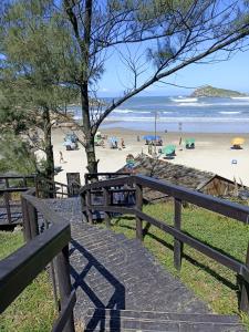 eine Holztreppe, die zu einem Strand mit Menschen führt in der Unterkunft Condomínio Residencial Mar Azul in Imbituba