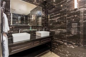 a black tiled bathroom with two sinks and a mirror at The Kylestrome in Ayr