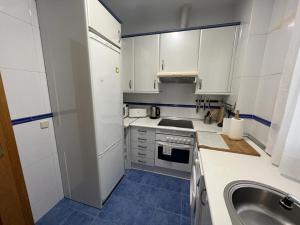 una pequeña cocina con armarios blancos y fregadero en Rooms Barco, en Madrid