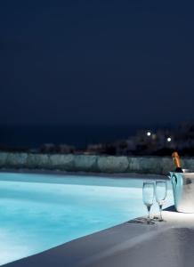 due bicchieri da vino seduti sul bordo di una piscina di Red Cliff Santorini Villa - Volcano View & Jacuzzi ad Akrotírion