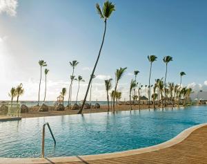 a swimming pool next to a beach with palm trees at Nickelodeon Hotels & Resorts Punta Cana - Gourmet All Inclusive by Karisma in Punta Cana