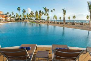 a swimming pool at a resort with chairs and palm trees at Nickelodeon Hotels & Resorts Punta Cana - Gourmet All Inclusive by Karisma in Punta Cana