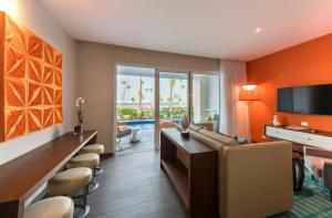 een woonkamer met oranje muren en een woonkamer met een bank bij Nickelodeon Hotels & Resorts Punta Cana - Gourmet All Inclusive by Karisma in Punta Cana