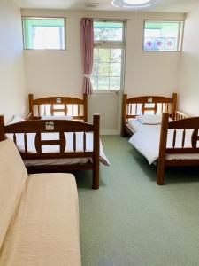 Zimmer mit 3 Betten in einem Zimmer mit Fenstern in der Unterkunft Pension L&M - Vacation STAY 82545v in Fuchisaki