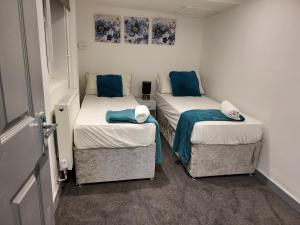 two twin beds in a small room with blue pillows at Vetrelax Southend Apartment in Westcliff-On-Sea