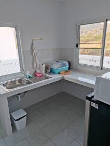 a kitchen with a counter and a sink and two windows at S&F villa in Sam Roi Yot