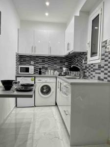 a kitchen with white cabinets and a washer and dryer at ATH Luxury Central apartment in Athens