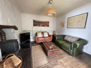 a living room with a green couch and a tv at Pier Cottage, Applecross in Applecross