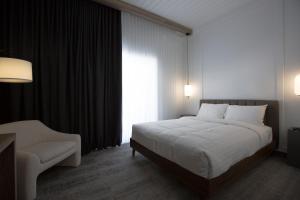 a bedroom with a bed and a chair and a window at Hotelia in Saint-Ambroise