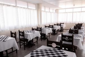 a restaurant with white tables and chairs and windows at ALVORADA PALACE HOTEL in Bauru