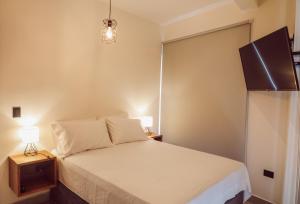 1 dormitorio con 1 cama y TV en la pared en Lahos Apartament B en Panajachel