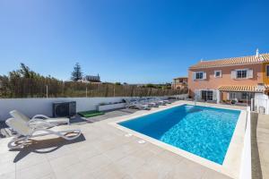 Una piscina con tumbonas al lado de una casa. en Sweet Home Sagres, en Sagres
