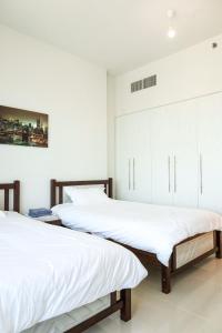 two beds in a bedroom with white walls at 2 Bedrooms in Al Reem Island Near Cleveland Clinic in Abu Dhabi