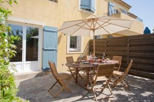 a table and chairs with an umbrella on a patio at Villa les Pensées La Londe in La Londe-les-Maures