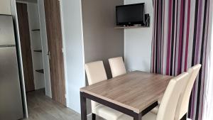une table à manger avec des chaises blanches et une télévision dans l'établissement Mobile Home Climatisé 3 chambres à Narbonne Plage, à Narbonne-Plage