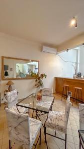 uma sala de estar com uma mesa de vidro e cadeiras em Central 9 Rooms em Ermoupoli