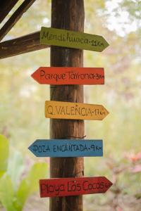 a wooden pole with signs pointing in different directions at Serrano Glamping in El Zaino