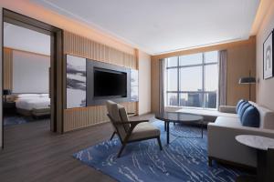 a living room with a couch and a tv at Courtyard by Marriott Foshan in Foshan