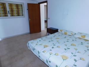 1 dormitorio con 1 cama con colcha de flores en Appartamento San Carlo, Condofuri (RC), en Condofuri Marina