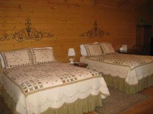 two beds in a bedroom with wooden walls at Pine Tree Inn in Panaca