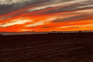 a sunset at the beach with people walking on the beach at 210 Forty Fourth Street in Newport Beach