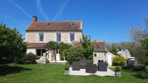 an old house with a group of chairs in the yard at Gite galets et bois flottés proche mer gold beach meublé de tourisme 4 étoiles in Meuvaines