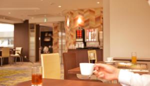 una persona seduta a un tavolo con una tazza di vino di Hotel New Gaea Domemae a Fukuoka