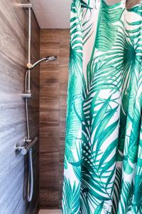 a bathroom with a shower with a green leafy shower curtain at Chichester retreat house with free parking in Chichester