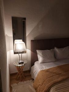 a bedroom with a bed and a table with a lamp at Casas Zé Pinto in Hospital