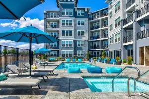 a pool with chairs and umbrellas in front of a building at Chic Apt w Jacuzzi, Pool, BBQ, & Mountain Views in Sparks