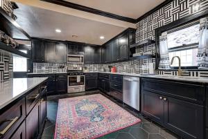 a kitchen with black cabinets and a rug on the floor at Boho Glam Bungalow mins away Western Ave Districts in Oklahoma City