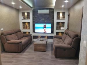 a living room with two couches and a flat screen tv at Paradise Swing Apartment Sofia in Sofia
