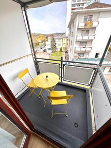 a balcony with a yellow table and two chairs at Business Apartment Lörrach in Lörrach