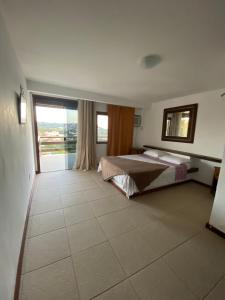 a bedroom with a bed and a large window at Suites Buzios in Búzios +32 photos