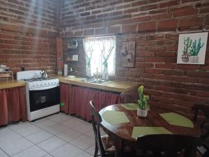 uma cozinha com uma mesa e uma parede de tijolos em CABAÑA LA GRULLA em Santa Verónica