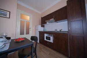 a kitchen with wooden cabinets and a table with a bowl of fruit at Apartman Bianca the Best in Rijeka