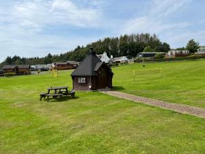 a small building with a picnic table in a field at Jungle House no.26 at Three Lochs Holiday Park in Newton Stewart