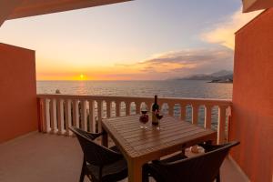 una mesa con 2 copas de vino en un balcón con puesta de sol en DreamSea Apartment, en Utjeha